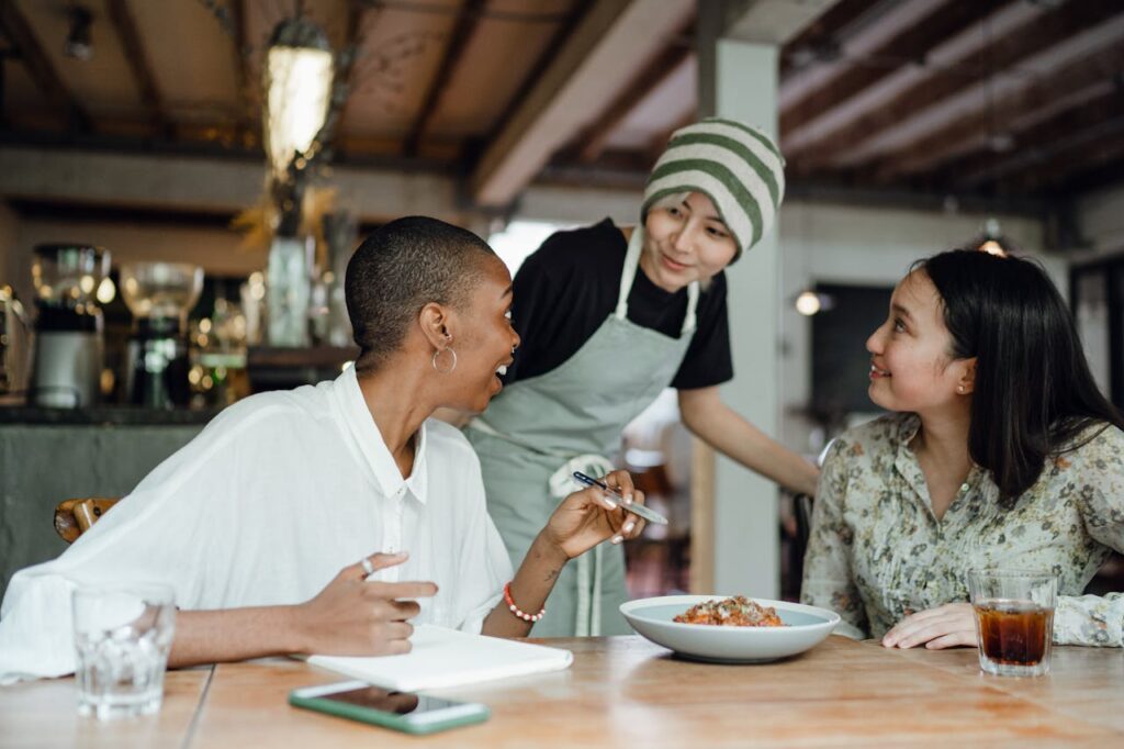 Three diverse small business owners in discussion at a cozy restaurant, embodying successful customer acquisition in Rockland County.