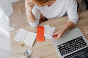 Small business owner analyzing receipts and managing finances on a laptop, reflecting effective cost management strategies.