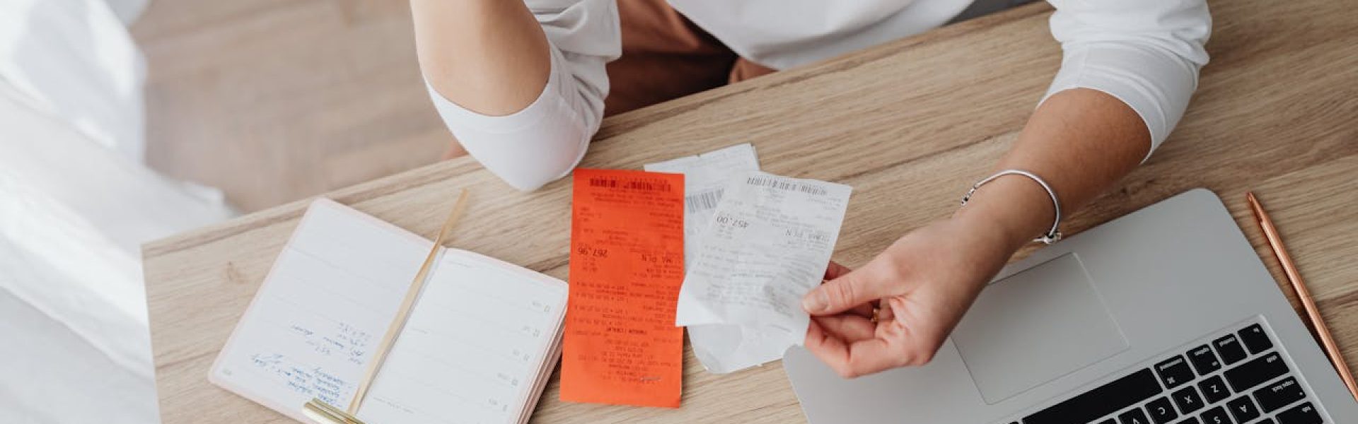 Small business owner analyzing receipts and managing finances on a laptop, reflecting effective cost management strategies.